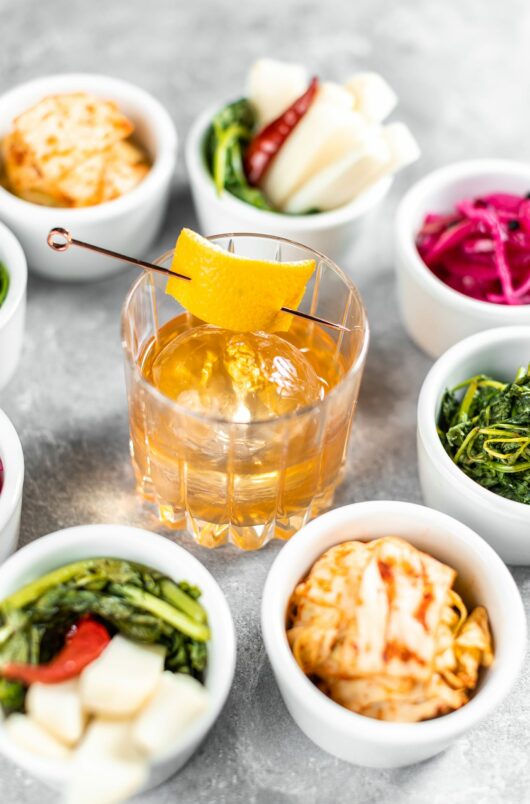 old fashion whiskey surrounded by korean side dishes